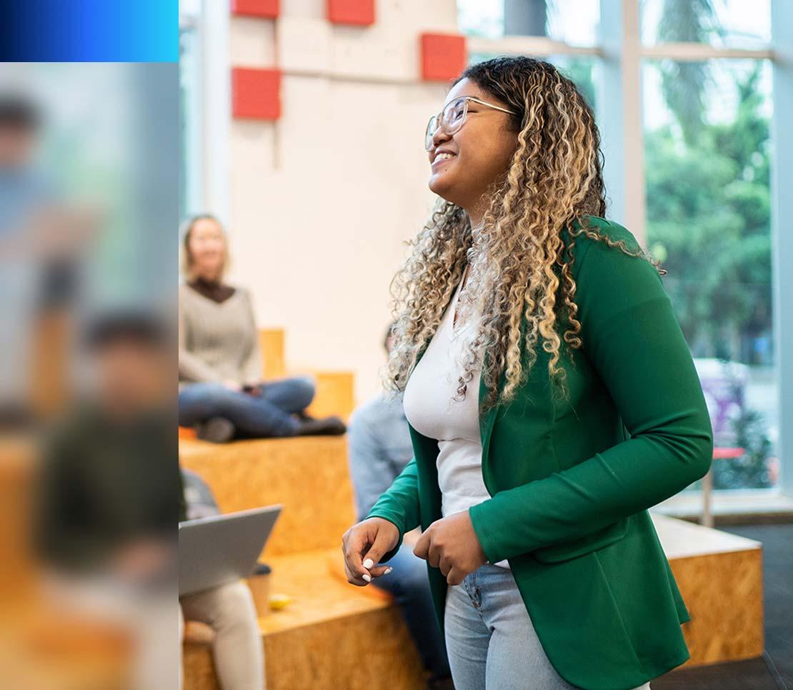 A woman in a green blazer converses with participants in a meeting dedicated to shaping the professionals of tomorrow.