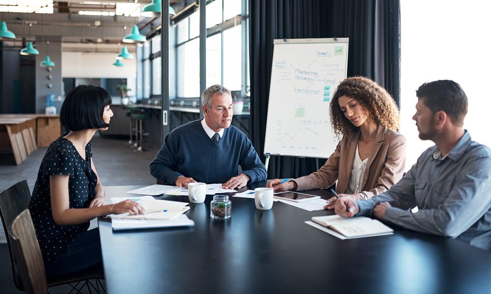  A diverse group of professionals collaborates around a table in an office setting, discussing threat management strategies.