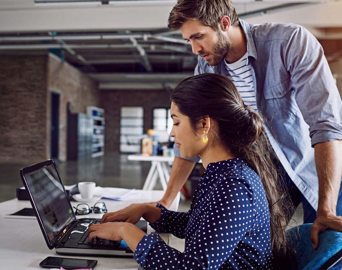 A man and woman collaborate on a laptop in an office, symbolizing teamwork in addressing security challenges.