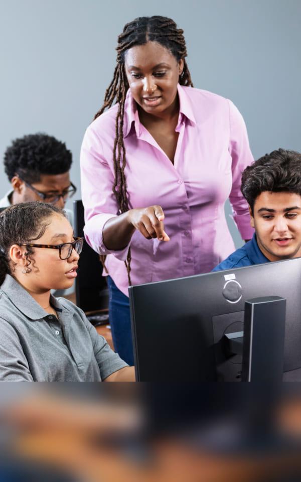 A woman leads a class of students at computers, highlighting strategies to strengthen cybersecurity in schools.