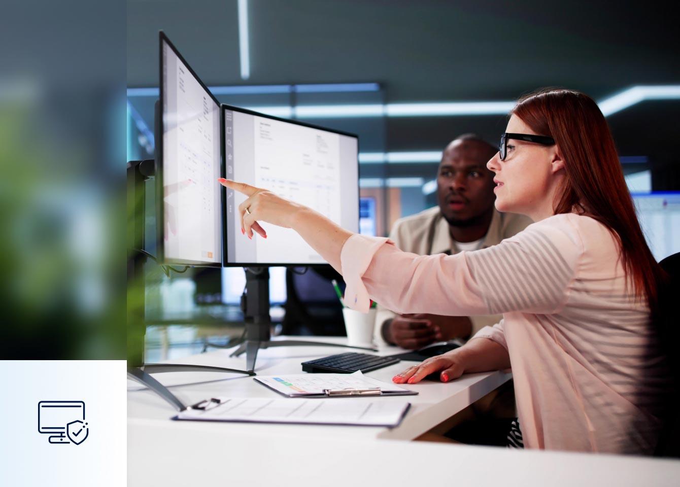A woman points at a computer screen, illustrating Unified Exposure Management and Threat Detection for risk reduction.