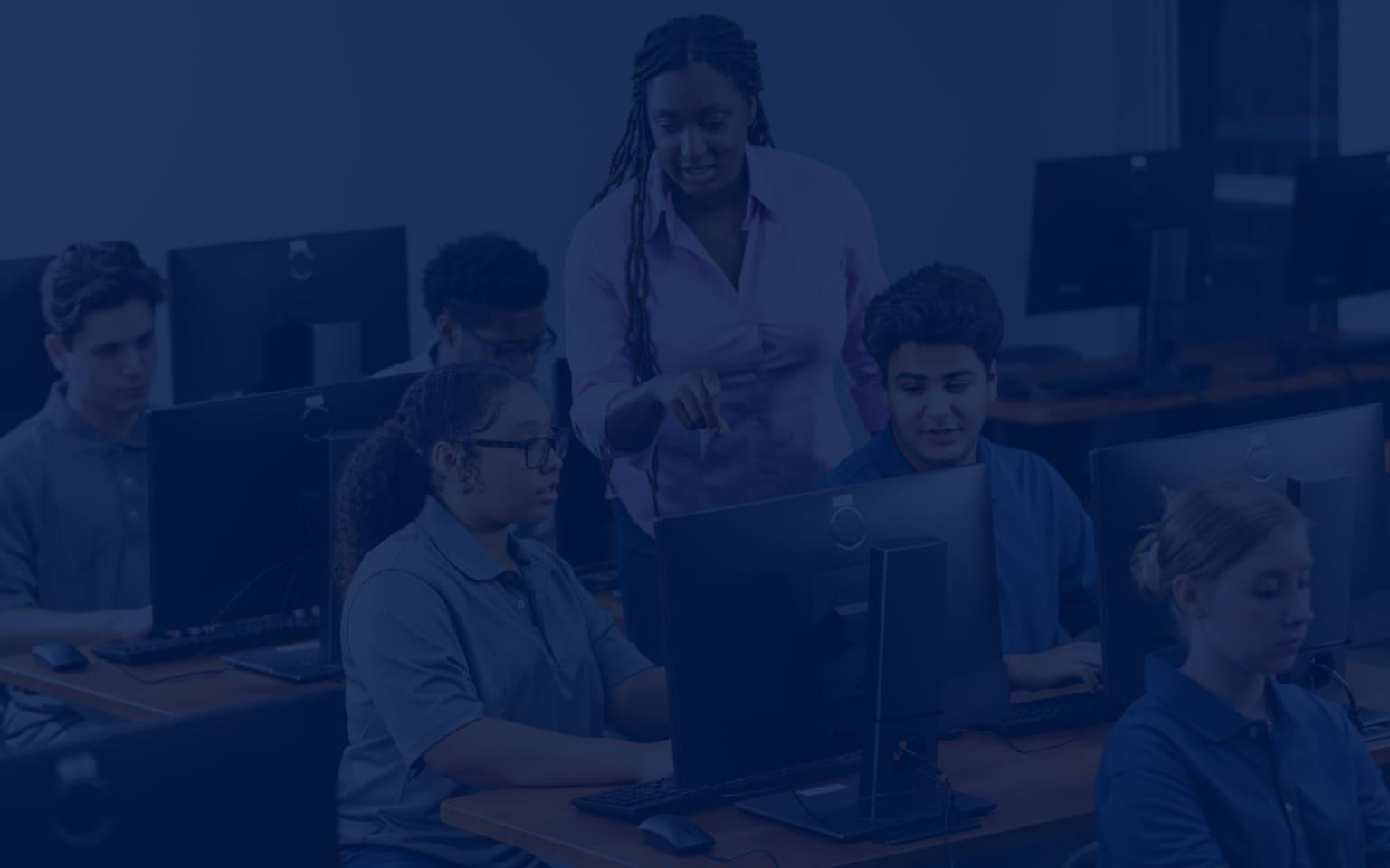 A woman leads a class of students at computers, highlighting strategies to strengthen cybersecurity in schools.