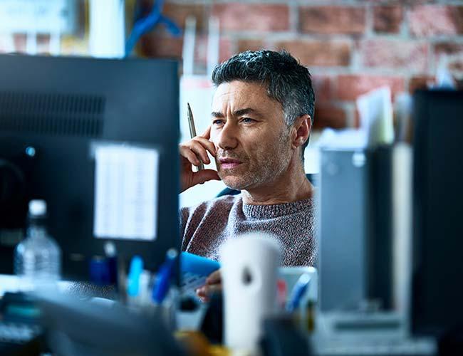  A man in an office environment, actively talking on the phone, illustrating a commitment to his professional duties.